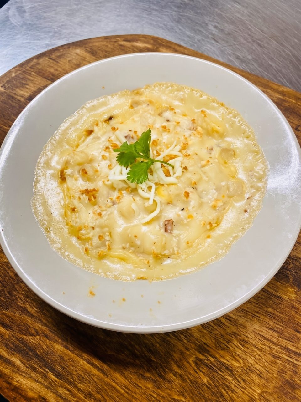 Creamy baked macaroni and cheese, topped with shredded cheese and a sprig of cilantro, on a white plate.